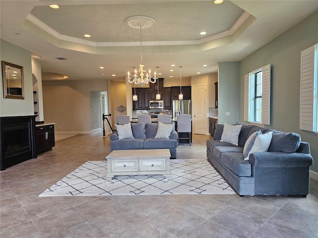 living room featuring a tray ceiling, an inviting chandelier, and ornamental molding