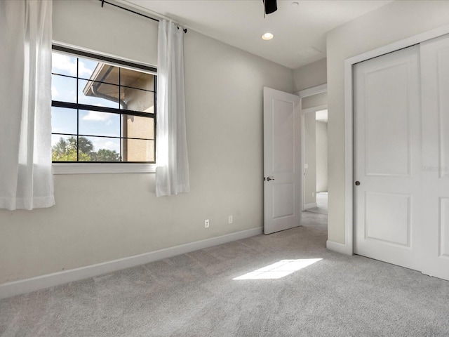 unfurnished bedroom featuring a closet, ceiling fan, and light colored carpet