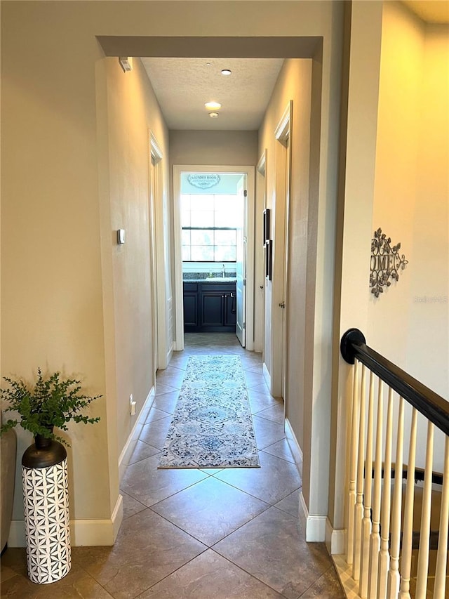 hall with tile patterned flooring, a textured ceiling, and sink