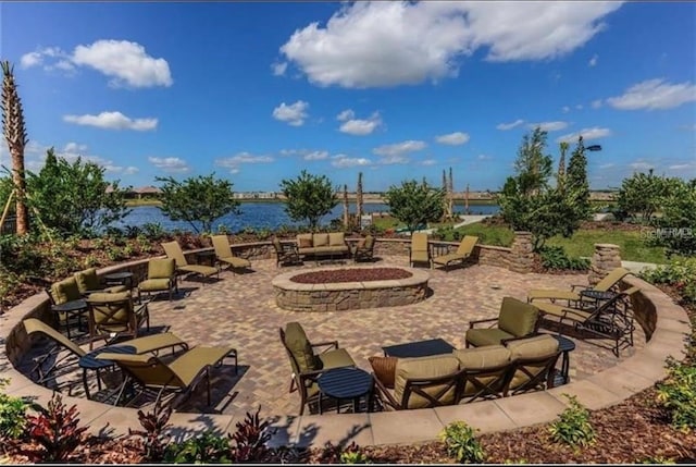 view of patio with a water view and an outdoor living space with a fire pit