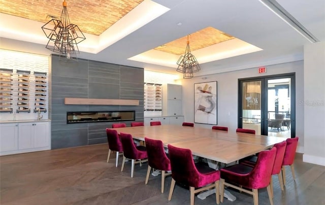 dining room with a raised ceiling, a fireplace, and parquet floors