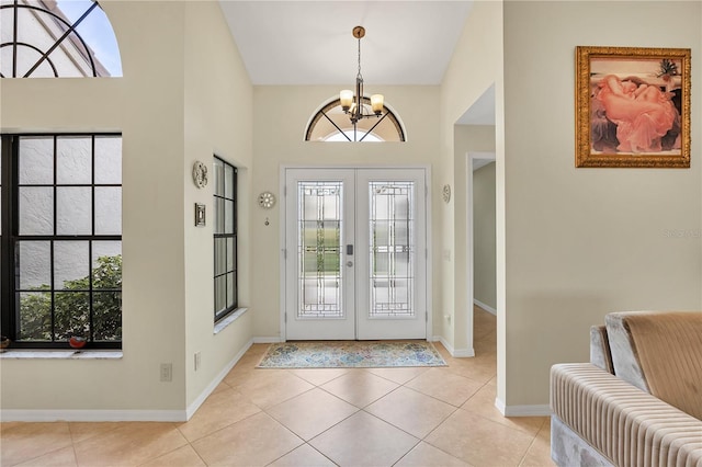 foyer entrance with french doors, a notable chandelier, light tile patterned flooring, and a high ceiling