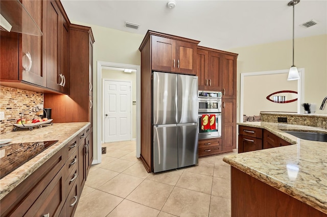 kitchen featuring tasteful backsplash, stainless steel appliances, light stone countertops, hanging light fixtures, and sink