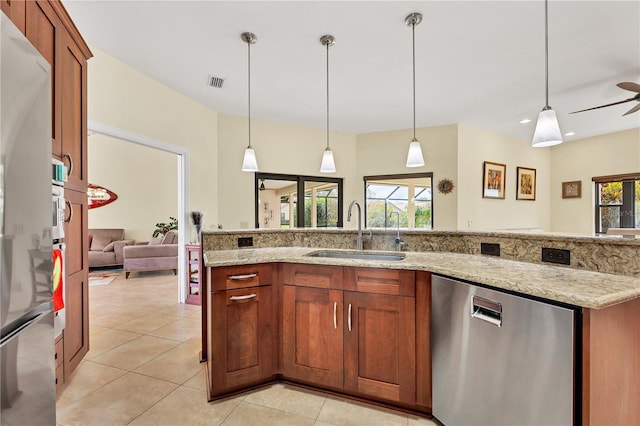 kitchen with stainless steel appliances, sink, decorative light fixtures, and light stone countertops