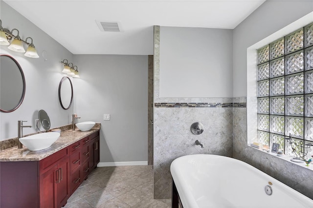 bathroom featuring vanity, tile walls, a tub, and tile patterned floors