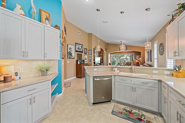 kitchen featuring sink, kitchen peninsula, light tile patterned floors, stainless steel dishwasher, and hanging light fixtures