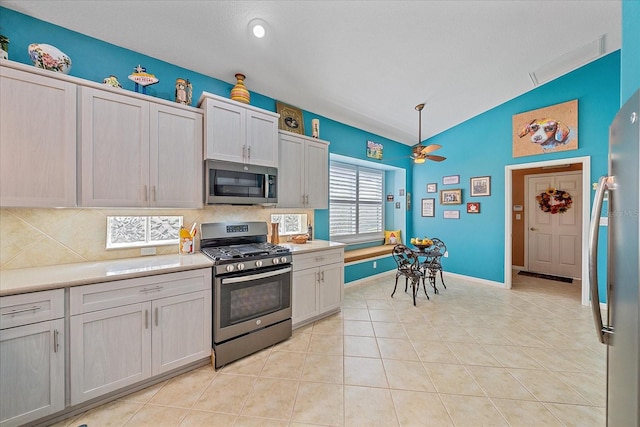 kitchen with lofted ceiling, decorative backsplash, light tile patterned flooring, and stainless steel appliances