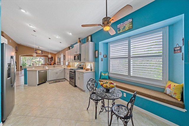 kitchen featuring appliances with stainless steel finishes, lofted ceiling, a healthy amount of sunlight, and hanging light fixtures