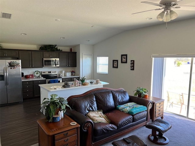 living room featuring vaulted ceiling, ceiling fan, and a textured ceiling