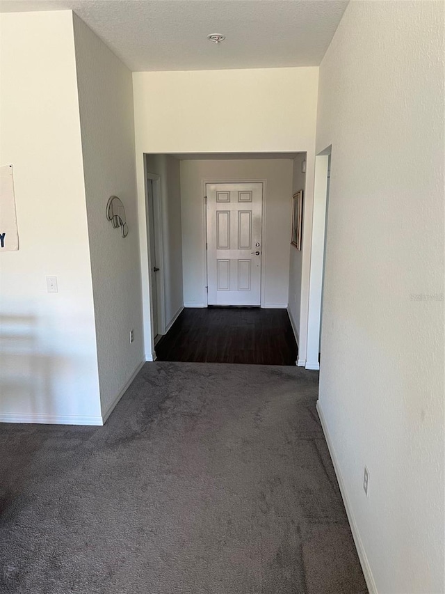 hall featuring dark colored carpet