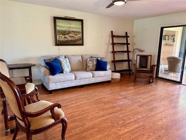 living room with ceiling fan, wood-type flooring, and a textured ceiling