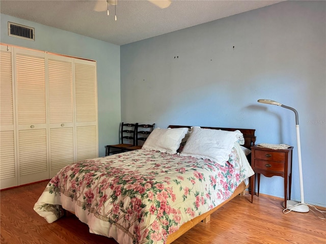 bedroom featuring ceiling fan, light wood-type flooring, and a textured ceiling