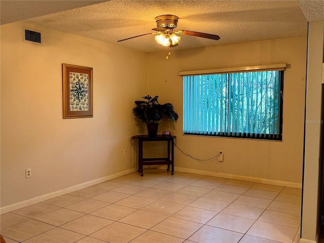 tiled empty room featuring a textured ceiling and ceiling fan