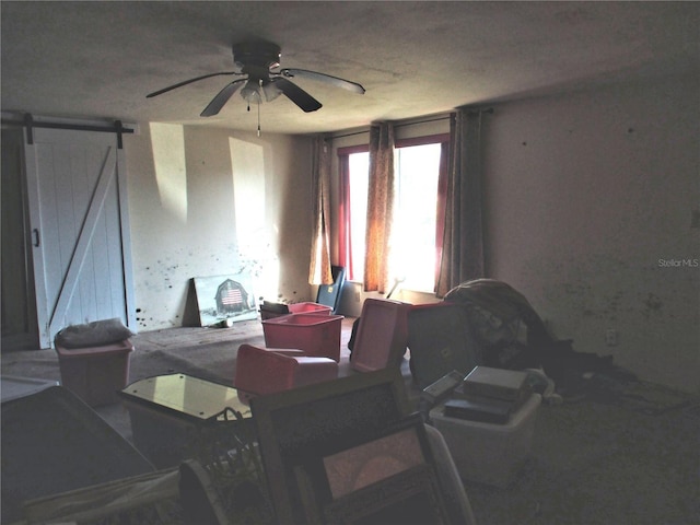 interior space with a barn door and ceiling fan