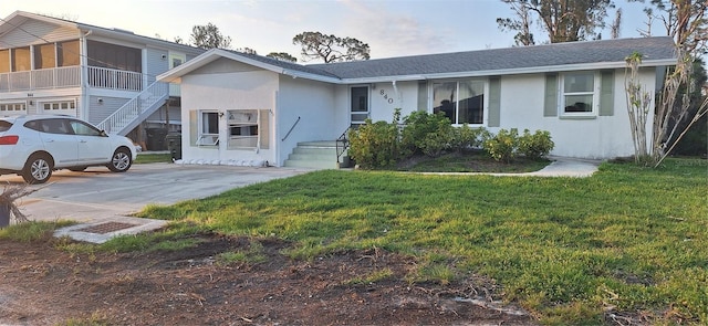 ranch-style house featuring driveway, a shingled roof, a front yard, and stucco siding