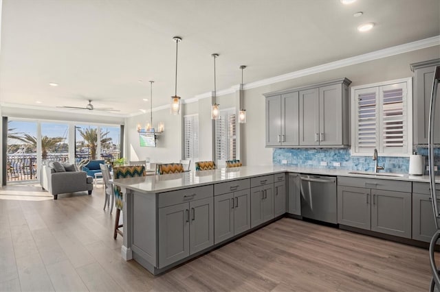 kitchen featuring dishwasher, kitchen peninsula, sink, a kitchen breakfast bar, and gray cabinets