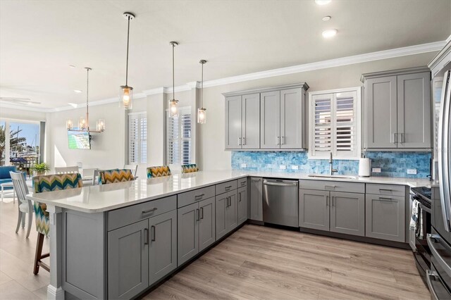 kitchen featuring hanging light fixtures, kitchen peninsula, stainless steel appliances, and a breakfast bar area