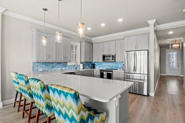 kitchen with stainless steel appliances, pendant lighting, a breakfast bar area, kitchen peninsula, and light hardwood / wood-style flooring