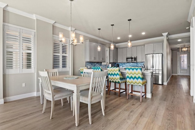 dining room featuring a notable chandelier, light wood-type flooring, and ornamental molding