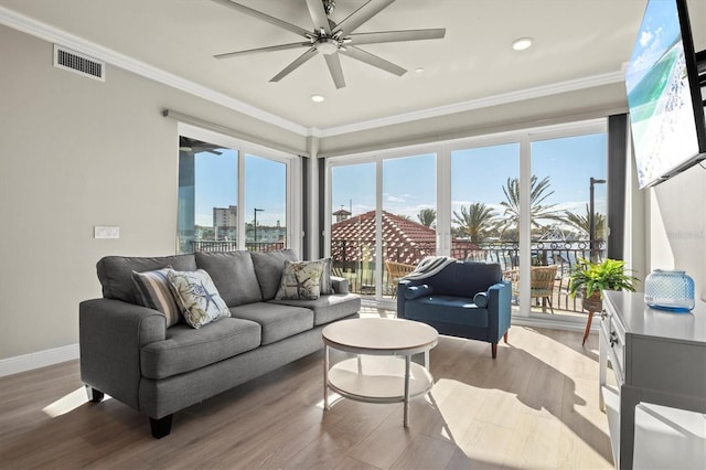 living room featuring hardwood / wood-style floors, ceiling fan, and crown molding