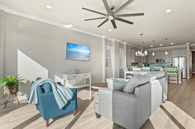 living room with light wood-type flooring, ceiling fan with notable chandelier, and crown molding