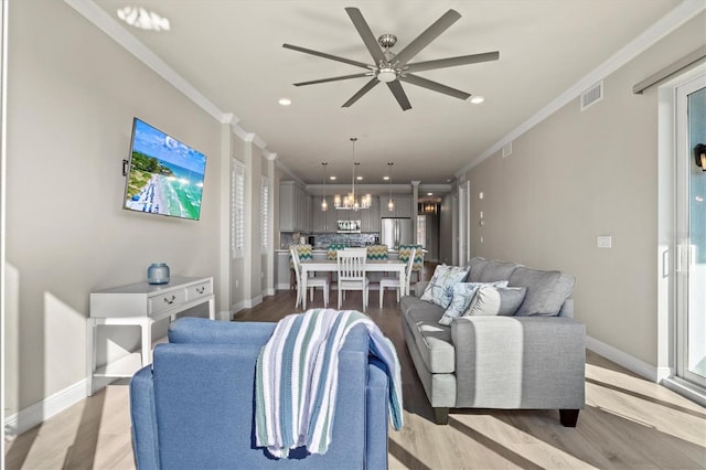 living room with light hardwood / wood-style floors, ceiling fan with notable chandelier, and crown molding