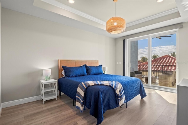 bedroom with crown molding, access to outside, wood-type flooring, and a raised ceiling