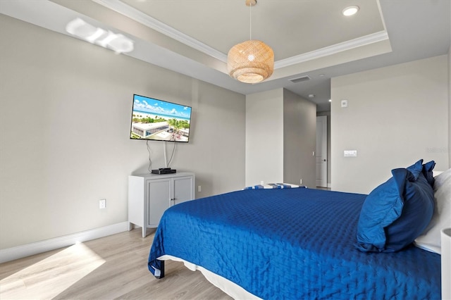 bedroom featuring light hardwood / wood-style flooring, crown molding, and a tray ceiling