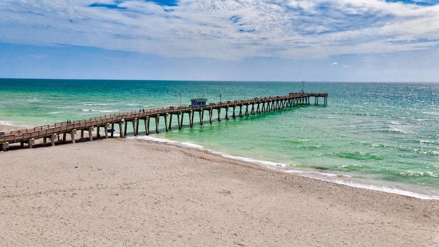 view of dock with a beach view and a water view