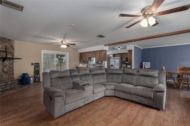 living room featuring ornamental molding, a textured ceiling, ceiling fan, and dark wood-type flooring