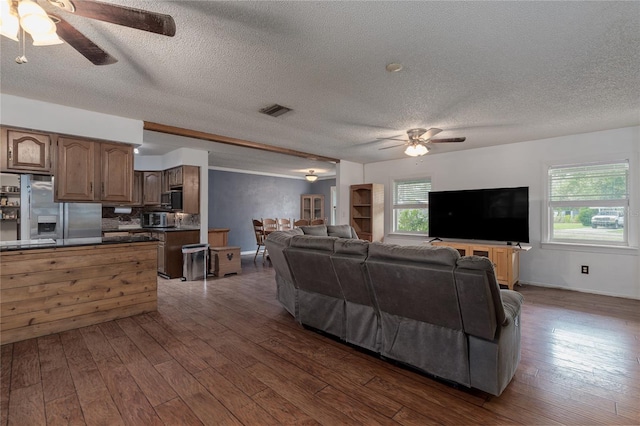 living room with ceiling fan, dark wood-type flooring, and a textured ceiling