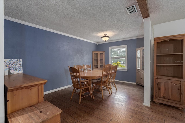 dining area featuring dark wood-type flooring, ornamental molding, and a textured ceiling