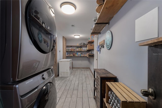 laundry area featuring light wood-type flooring and stacked washer and dryer