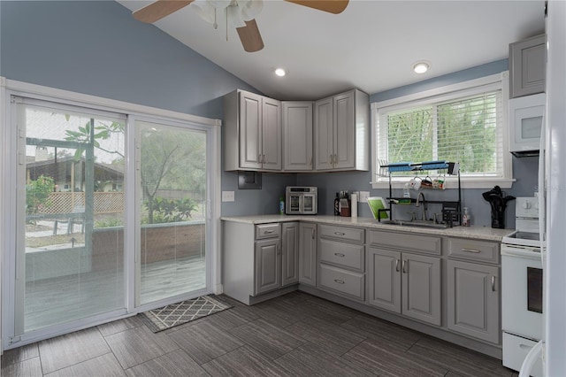 kitchen with gray cabinetry, lofted ceiling, a healthy amount of sunlight, and white appliances