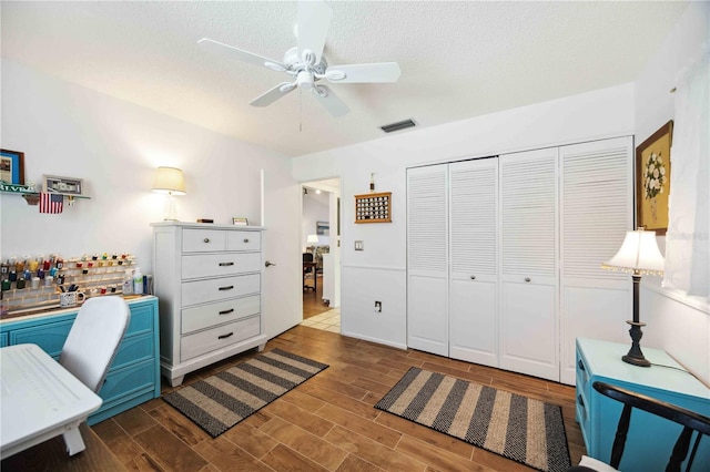 home office with a textured ceiling, a ceiling fan, visible vents, and wood tiled floor