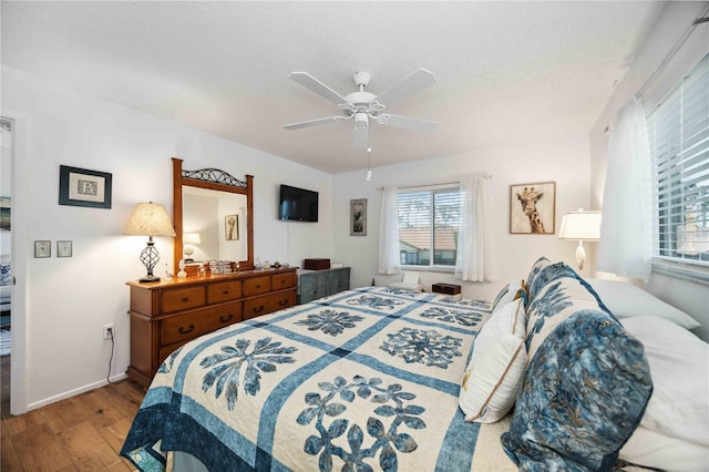 bedroom with ceiling fan, a textured ceiling, baseboards, and wood finished floors