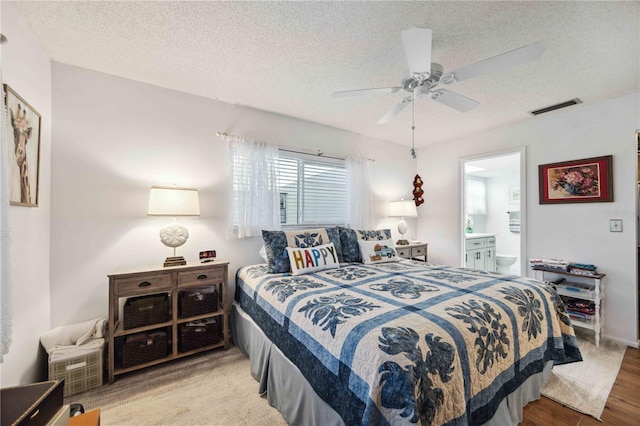 bedroom with visible vents, a textured ceiling, and ensuite bath