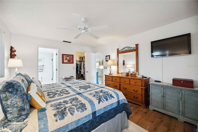 bedroom featuring a ceiling fan, a spacious closet, dark wood-style floors, and visible vents