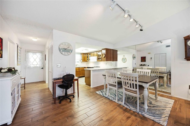 dining space with visible vents, lofted ceiling, and wood finished floors