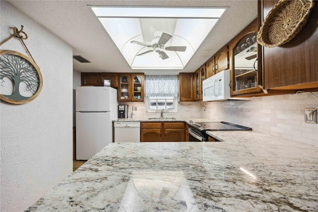 kitchen featuring white appliances, brown cabinetry, visible vents, a sink, and a textured wall