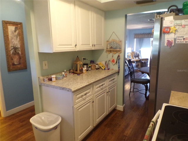 kitchen with stainless steel fridge, white cabinetry, and dark wood-type flooring