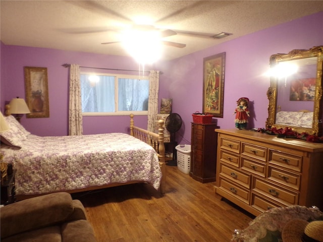 bedroom with ceiling fan, a textured ceiling, and hardwood / wood-style flooring