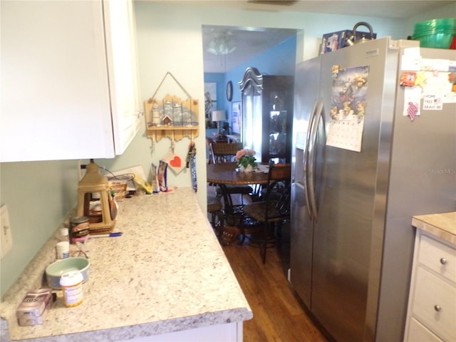 kitchen featuring stainless steel fridge, white cabinetry, and dark wood-type flooring