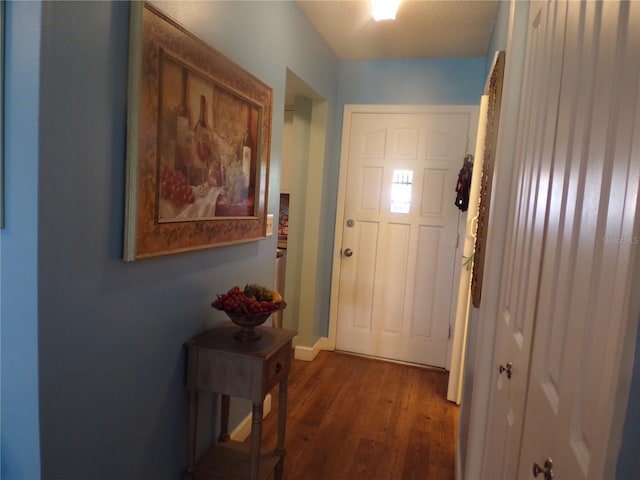 doorway to outside with dark wood-type flooring and a textured ceiling