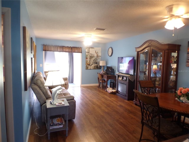 living room featuring a textured ceiling, dark hardwood / wood-style floors, and ceiling fan