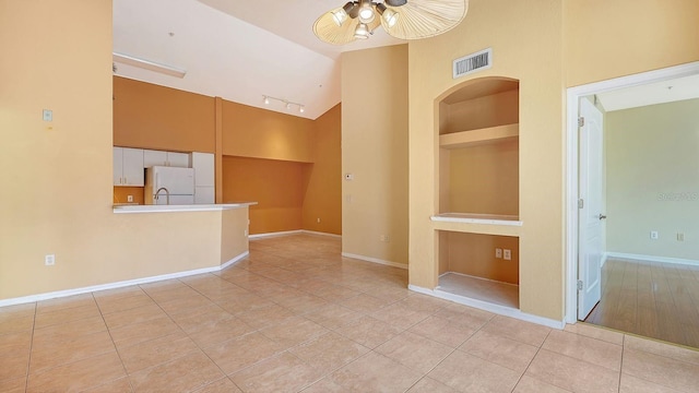 tiled spare room featuring built in shelves, high vaulted ceiling, and ceiling fan