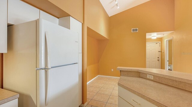 4134 Central Sarasota Pkwy Unit 1734, Sarasota, FL 34238 - kitchen with freestanding refrigerator, light tile patterned floors, high vaulted ceiling, white cabinets, and light countertops