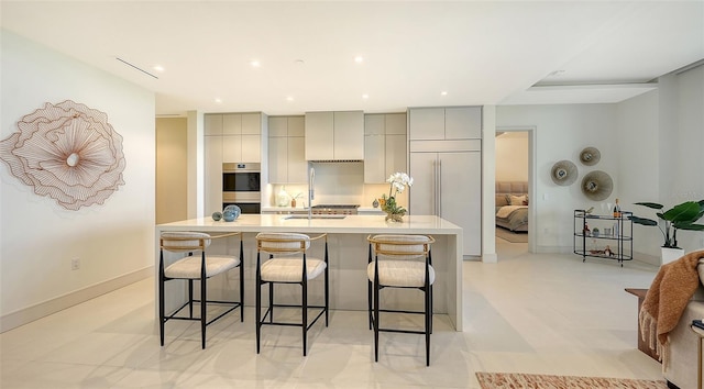 kitchen featuring gray cabinets, a large island with sink, and a breakfast bar