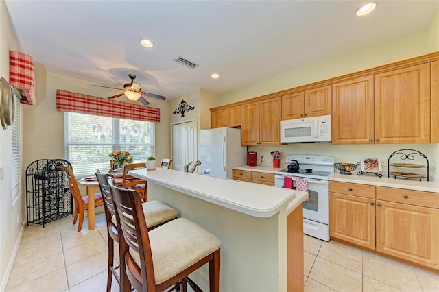 kitchen with ceiling fan, a kitchen island, light tile patterned flooring, and white appliances