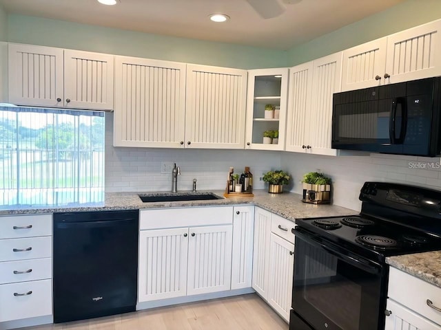 kitchen featuring white cabinets, sink, black appliances, and light stone counters